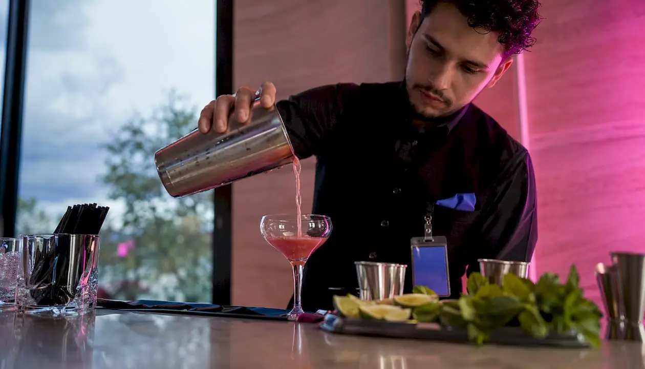 Hands pouring cocktail at licensed bartender station