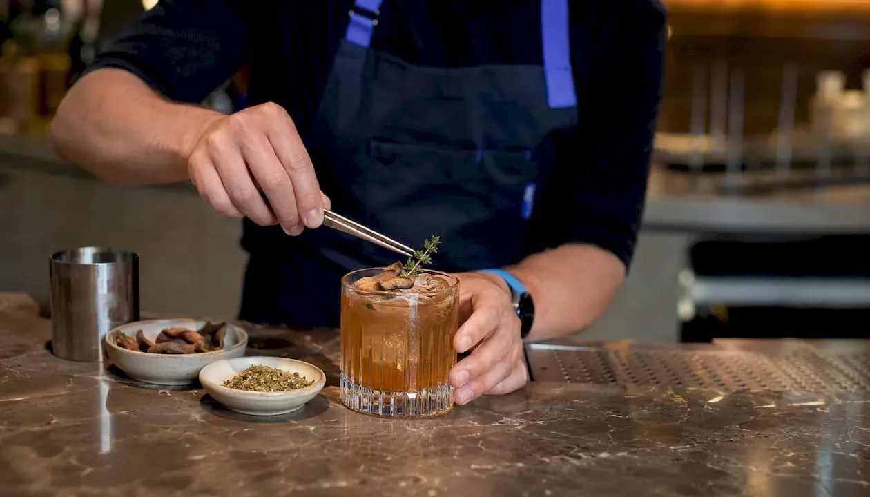 Bartender adding garnish to umami cocktail