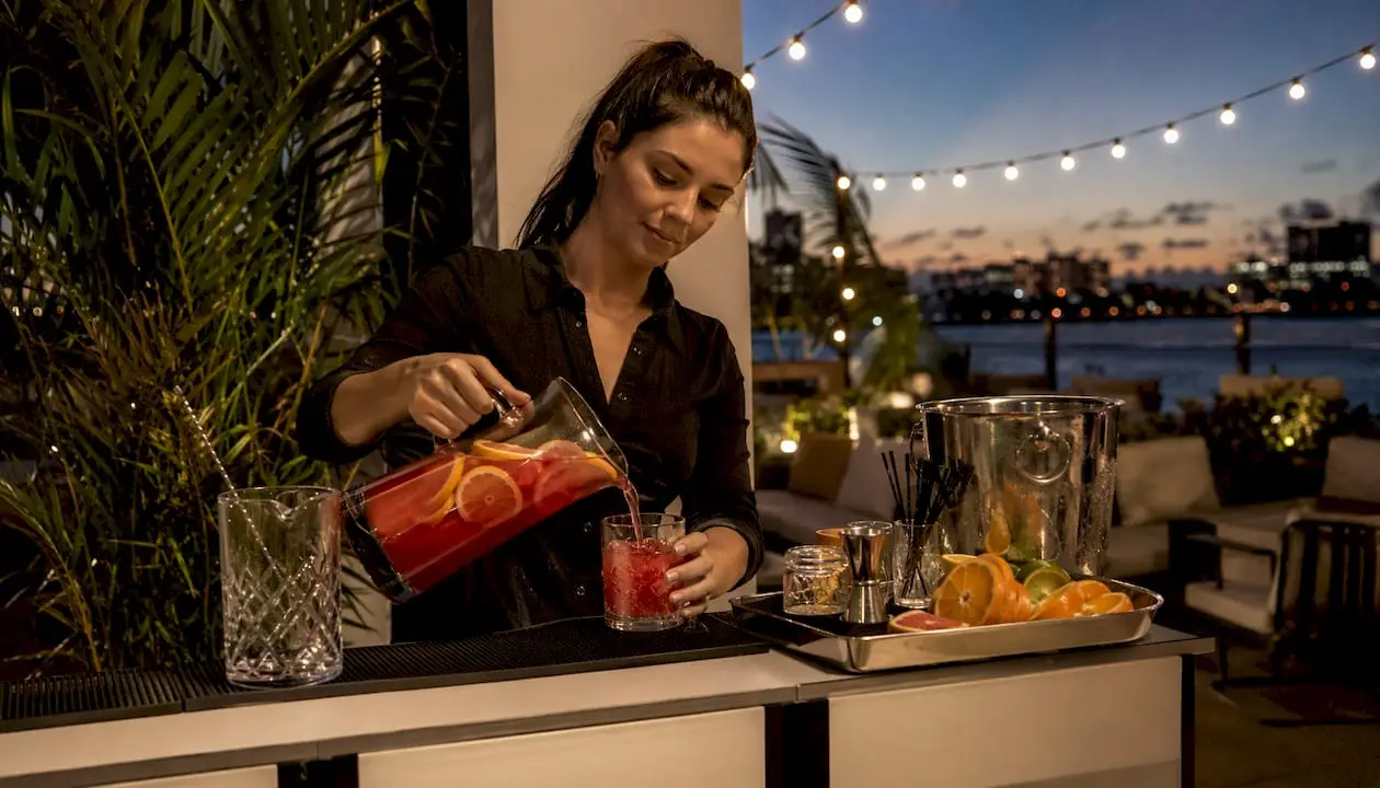 Bartender pouring batched cocktail in home bar setting
