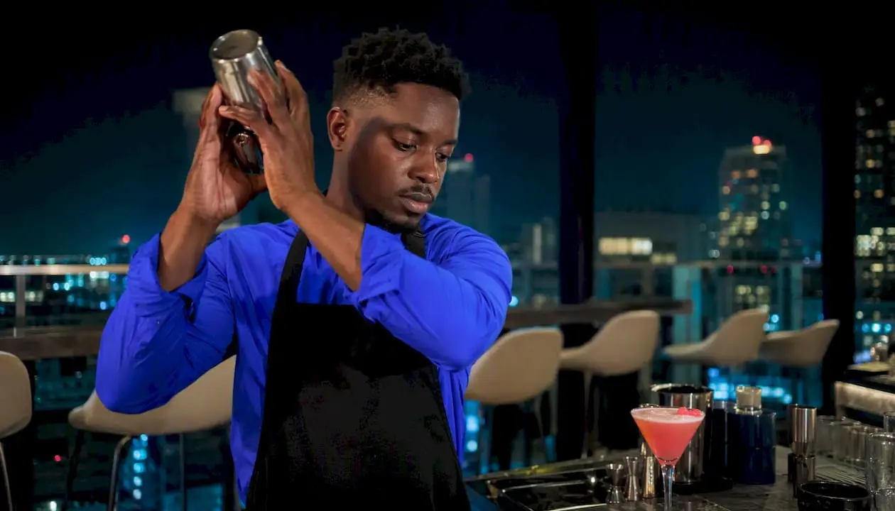 Professional bartender pouring cocktail at event bar