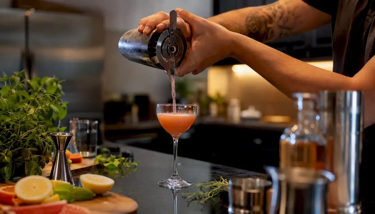 Bartender pouring cocktail in home bar