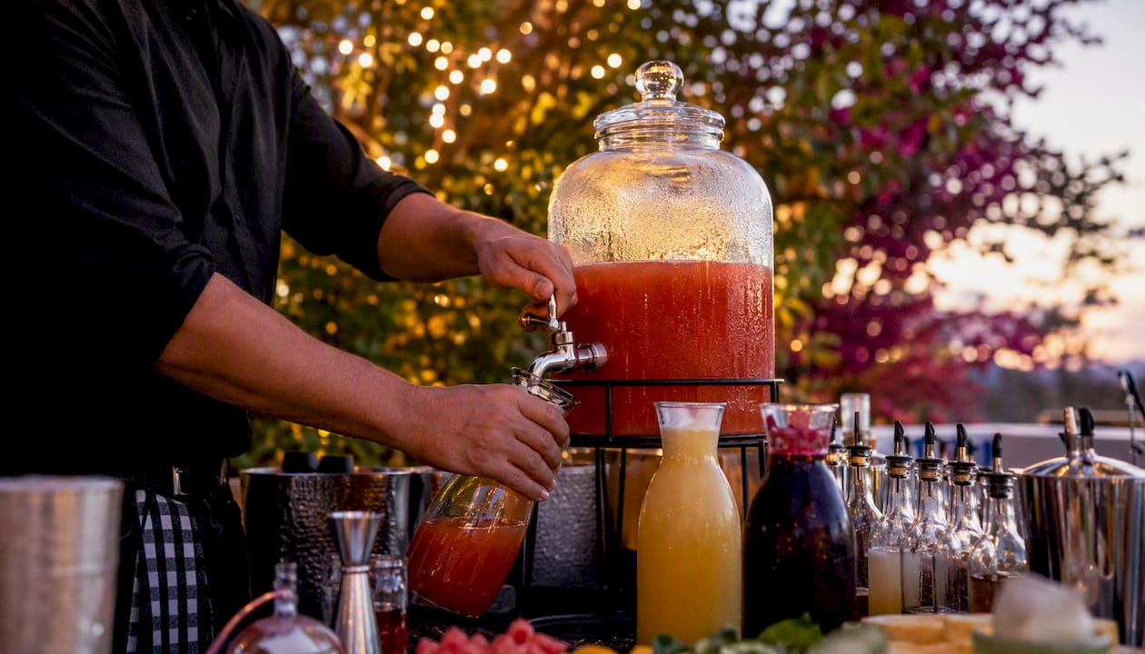 Bartender batching cocktail base in dispenser