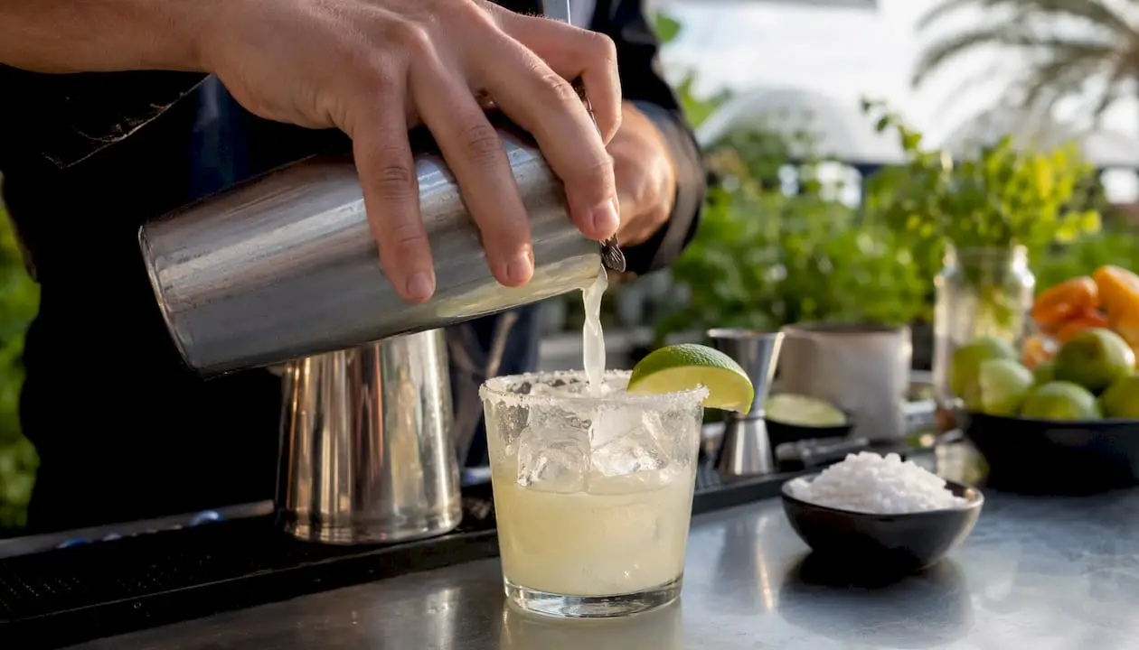 Pouring classic margarita cocktail over ice
