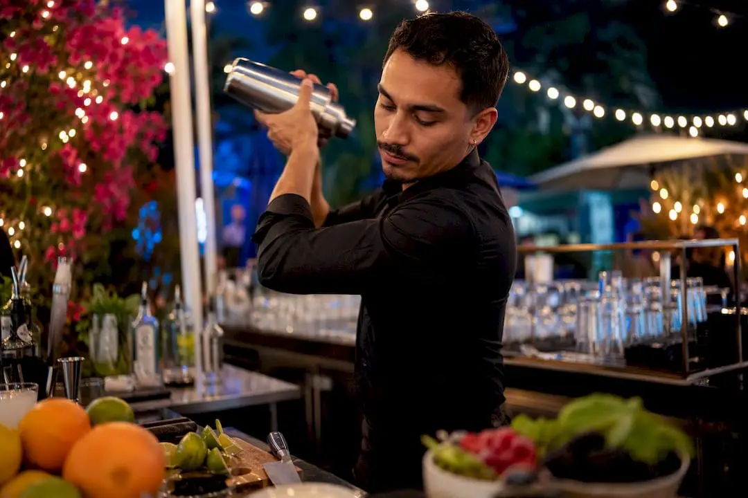 Bartender pouring vegan cocktail into glass