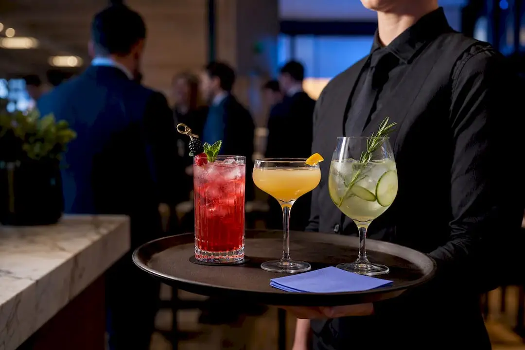 Server presenting three elevated event mocktails